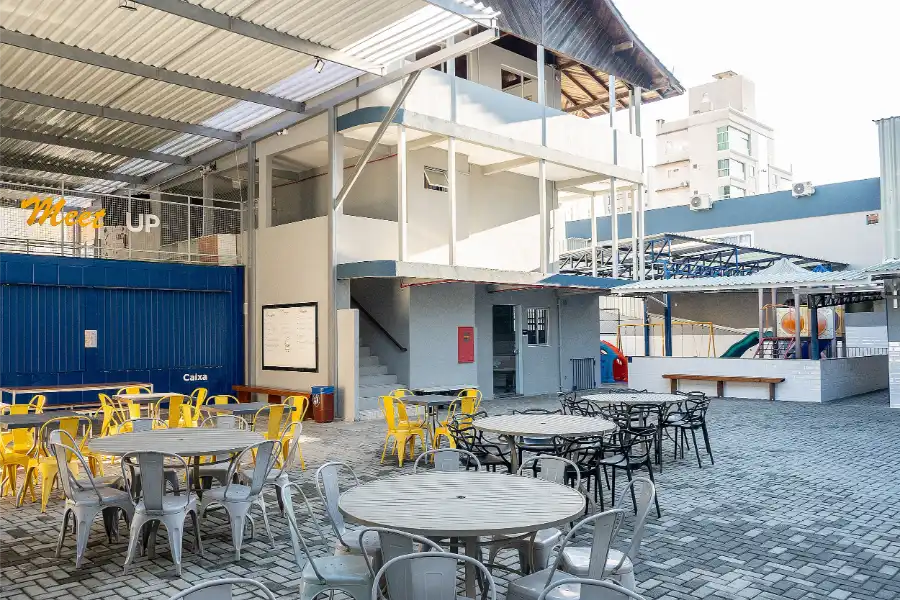 Área de convivência do Colégio Atlântico com mesas e cadeiras no espaço Meet Up, ambiente coberto destinado à integração e alimentação dos alunos.